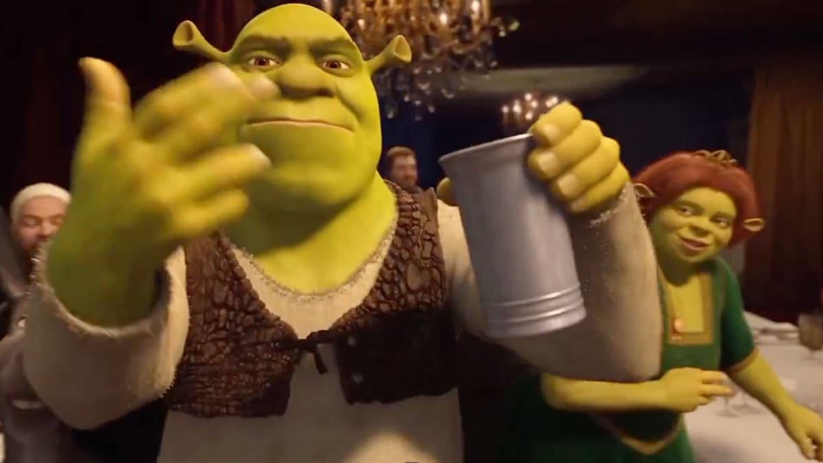 AI-generated version of the Drake party scene: Shrek waving at the camera and holding a metal cup in a dim dining room with a chandelier, Princess Fiona in a green dress smiling behind him on the right, a man in a white head wrap blurred at left